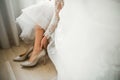 Bride puts on elegant and stylish bridal shoes on her tender feet