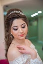 The bride puts her hand on her shoulder and takes a picture at the wedding. Wedding photo session in a beauty salon.The bride put