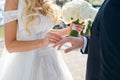 The bride puts a wedding ring on the groom finger, a beautiful wedding ceremony with fresh flowers, a beautiful girl and a Royalty Free Stock Photo