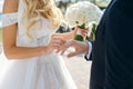 The bride puts a wedding ring on the groom finger, a beautiful wedding ceremony with fresh flowers, a beautiful girl and a Royalty Free Stock Photo