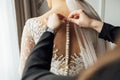 The bride puts on a white lace wedding dress, mom and girlfriend of the bride help to tie the dress from the back. Royalty Free Stock Photo