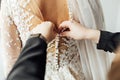 The bride puts on a white lace wedding dress, mom and girlfriend of the bride help to tie the dress from the back. Royalty Free Stock Photo