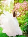 Bride Rear View in Wedding Dress with Train waving on Wind in blooming Garden. Beautiful Woman in bridal White Gown looking away Royalty Free Stock Photo