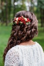 Bride with red natural flowers and greenery in her hair. Portrait of attractive young woman with beautiful hairstyle and stylish h Royalty Free Stock Photo