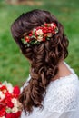 Bride with red natural flowers and greenery in her hair. Portrait of attractive young woman with beautiful hairstyle and stylish h Royalty Free Stock Photo