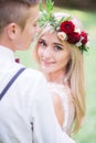 Bride in red wreathe stands hidden behind a groom