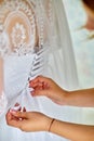 Bride in the room. Bbeautiful young girl preparing for the wedding and someone is helping to put on a white dress