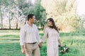 The bride in rustic style with a beautiful wreath on the head of flowers with a bouquet in hands in a park in white