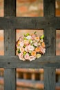 The bride s bouquet lies in the cell of a large wooden lattice, which is the gateway to the ancient church Royalty Free Stock Photo