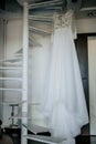 Bride`s dress on hanger on the stairs in the bride room. Wedding day