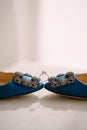 Bride`s engagement ring with a large gemstone between blue shoes with a jewel decoration.