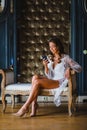 Young beautiful bride in white negligee watching a message in her smartphone Royalty Free Stock Photo