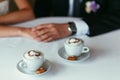 Bride's and groom's hands holding each other on a table with two Royalty Free Stock Photo