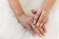 The bride& x27;s hands finger adjust the ring on the white dress. Wedding ring close-up bride& x27;s hand on dress.