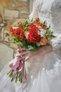 bride's hands hold a wedding bouquet of red and pink roses tied with pink ribbons. beautiful manicure  lace white Royalty Free Stock Photo