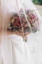 Bride`s hands holding modern a beautiful, stylish wedding bouquet of purple, pink roses and eucalyptus greenery. Royalty Free Stock Photo