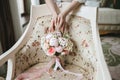 The bride`s hands touch a beautiful wedding bouquet of pink and white peonies, which stands on a vintage beige chair Royalty Free Stock Photo