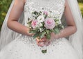 The bride`s hands in a wedding white dress hold a bouquet of flowers close up Royalty Free Stock Photo