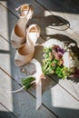 Bride's shoes, a beautiful wedding bouquet and rings are beautifully laid out on a wooden background Royalty Free Stock Photo