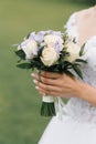 The bride`s wedding bouquet of milk roses and lilac eustoms in the hands of the bride