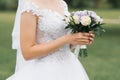 The bride`s wedding bouquet of milk roses and lilac eustoms in the hands of the bride