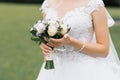 The bride`s wedding bouquet of milk roses and lilac eustoms in the hands of the bride close-up