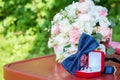 Bride`s wedding bouquet of white and pink flowers. Blue bow tie next to gold wedding rings in a red box. White and pink roses. Royalty Free Stock Photo