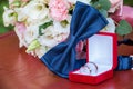 Bride`s wedding bouquet of white and pink flowers. Blue bow tie next to gold wedding rings in a red box. White and pink roses. Royalty Free Stock Photo