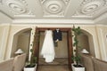 The bride's wedding dress and the groom's jacket on wooden hangers, hang on the wardrobe Royalty Free Stock Photo