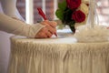 The bride signs on the marriage certificate, a bouquet of white and red roses on the table