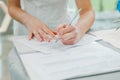 The bride signs the marriage registration documents. Young couple signing wedding documents.