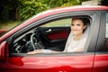 The bride sits behind the stering wheel of a red sports car