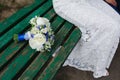 The bride sits on a bench next to wedding bouquet