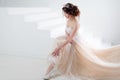 Bride sits on the stairs. Portrait of a beautiful girl in a wedding dress. Dancing Bride, white background. Royalty Free Stock Photo