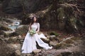 The bride sits on stones high in the mountains by the river Royalty Free Stock Photo