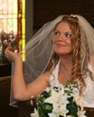 Bride sitting in a church pew holding her veil Royalty Free Stock Photo