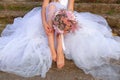 Bride sitting on the stone steps and holding wedding bouquet Royalty Free Stock Photo