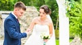 Bride slipping ring on finger of groom at wedding