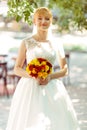 Bride smiles standing with a bouqet on a street in shiny morning Royalty Free Stock Photo