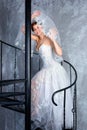 Bride standing on spiral staircase in loft apartment. Woman dressed in wedding dress with lace, copy space for text Royalty Free Stock Photo