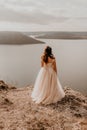 bride stands on a cliff against the background of the river and islands