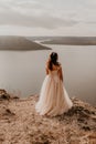 bride stands on a cliff against the background of the river and islands