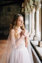 Bride stands with her arms crossed on her chest on a loggia with columns in an old villa on Lake Como. Close up Royalty Free Stock Photo
