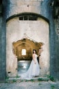 Bride stands near the dilapidated entrance of the old fortress