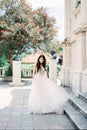 Bride stands near the steps of a stone building against the backdrop of a flowering tree