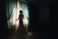 Bride stands before the window covered with green curtains