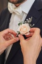 the bride straightens the groom's boutonniere pink rose