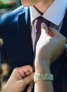 Bride straightens to groom his tie, close-up of hands