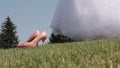 Bride takes her shoes off grass in a wedding dress