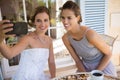 Bride taking selfie with bridesmaid in yard